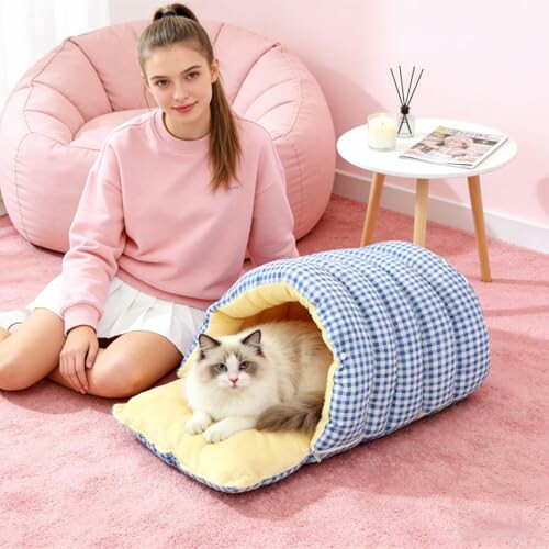 Mädchen sitzt neben einer Katze in einem Katzentunnel.