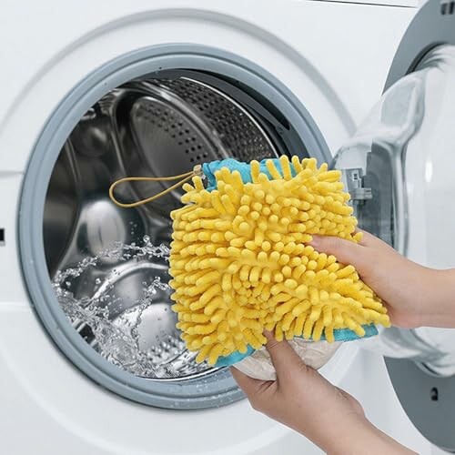 Person reinigt Waschmaschine mit gelbem Tuch.